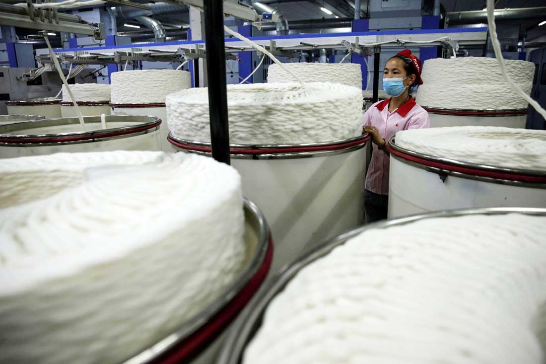 Работник у прядильного станка на фабрике текстильной компании Aksu Huafu в китайском регионе Синьцзян.