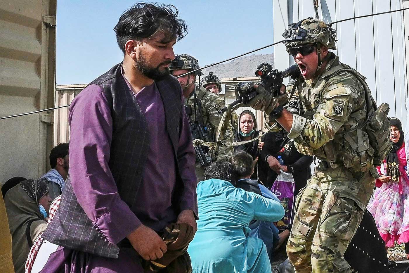 Американский солдат нацеливает оружие на афганского пассажира в аэропорту Кабула в понедельник 16 августа 2021 года, когда тысячи людей осаждали аэропорт, чтобы покинуть страну.