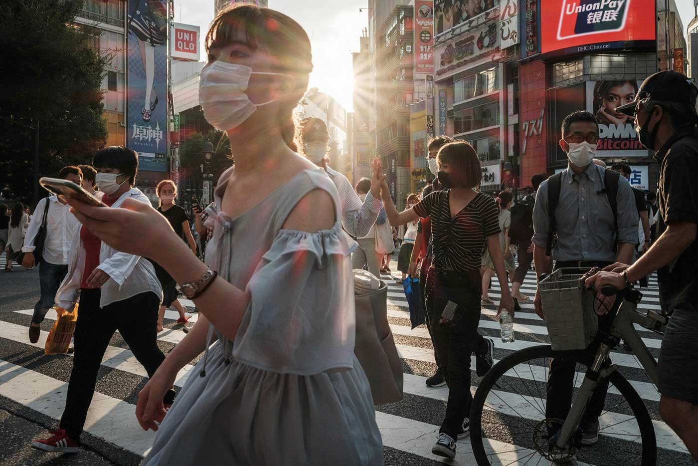   Жители Токио в лицевых масках. Некоторые страны боролись за доступ к вакцинам, поскольку другие страны, которые уже имели производственные объекты, ввели экспортный контроль, чтобы обеспечить приоритетную вакцинацию своих граждан.