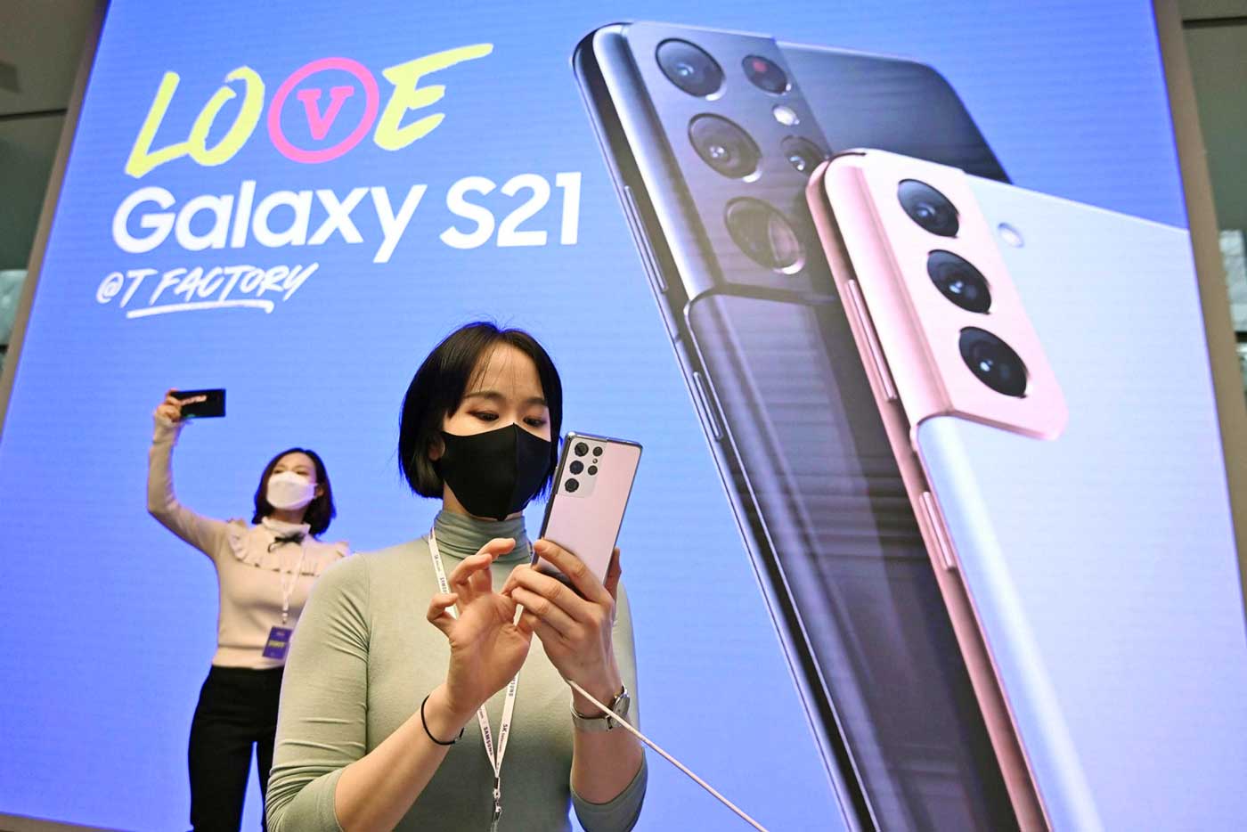 Женщина со смартфоном Samsung Galaxy S21 во время его презентации в Сеуле. Samsung является крупнейшим в мире производителем компьютерных микросхем, смартфонов и электронных дисплеев.